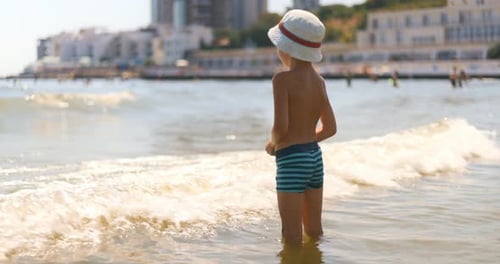 Child Playing in Shallow Sea Waves at Beach
