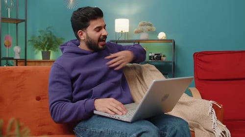 Young Man Video Conferencing at Home on Laptop