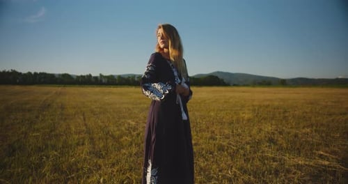 A romantic village girl in an embroidered shirt and in ukrainian vyshyvanka stands in a wheat field