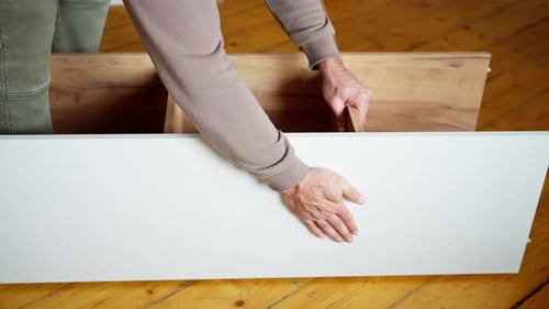 Man Assembling Wooden Shelf on Wooden Floor