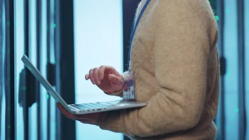 An IT Professional Engaged in Working on a Laptop Inside a Modern Data Center Facility