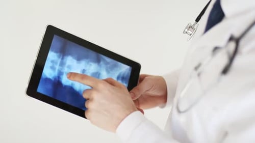 Professional doctor examining x-ray scan on tablet pc in modern hospital lab