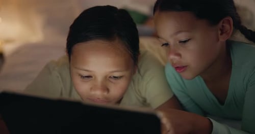 Girls Using Tablet Computer Together at Night