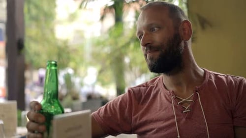 Young man enjoying a refreshing beer and relaxing outdoors in a city cafe