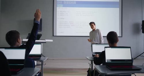 Klassenkameraden diskutieren im Programmierunterricht in der Schule über die wissenschaftliche Arbeit eines Schülers