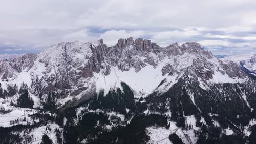 Aerial view of snowy mountains and forests in winter, Italy.