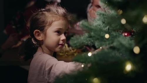 Child Decorating Christmas Tree with Lights at Night