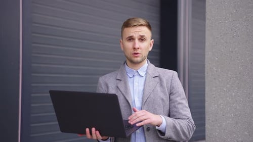 Joven gerente masculino que trabaja con una computadora portátil hablando con su colega Cámara lenta