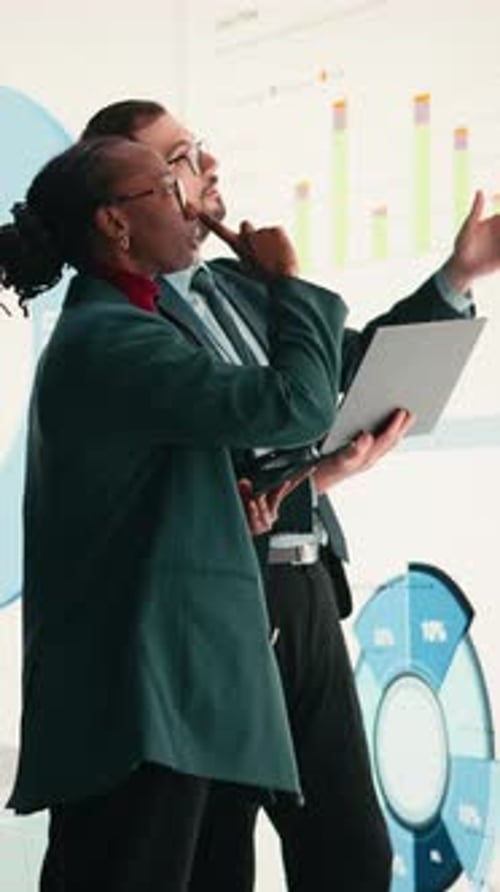 Vertical Video Corporate Managers Evaluate Fiscal Performance Metrics on Digital Wall