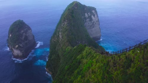 Vista aérea dos caminhantes, no topo de um penhasco íngreme que se estende até o vasto mar. Nusa Penida. Bali.