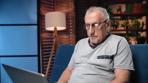Senior Man Using Laptop Computer on Couch at Home