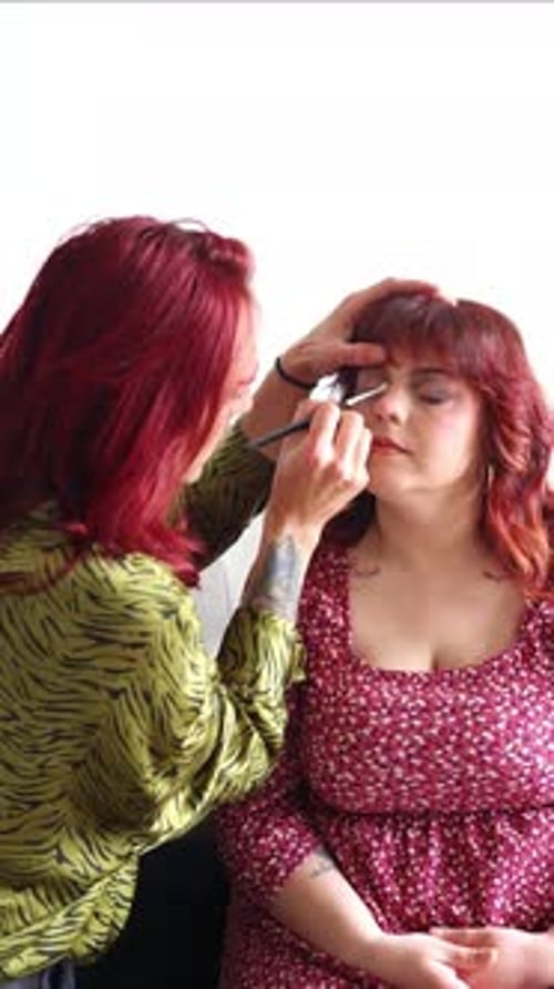 vertical Makeup artist applying makeup on a curvy non-binary person