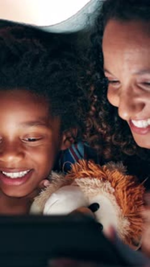 Mother and Child Reading Tablet Under Blanket at Night