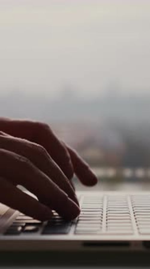 Woman working on laptop typing on keyboard, close up of fingers. Vertical video
