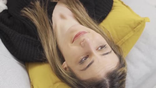 Woman Relaxes on Couch with Yellow Pillow