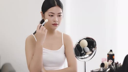 Slow motion shot Close up beauty young pan Asian woman looking at a mirror and applying cosmetics.