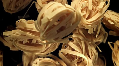 Uncooked Egg Ribbon Pasta Nests on Black Background