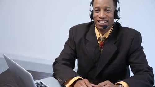 Smiling Man in Suit Wearing Headset at Desk