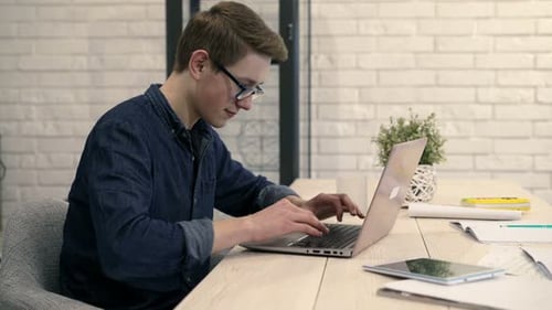 Man Typing on Laptop Computer at Desk Indoors