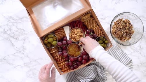 Person Packing Charcuterie Box with Cheese Meats Crackers