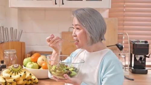 Senior Woman Enjoys a Nutritious Salad in Kitchen