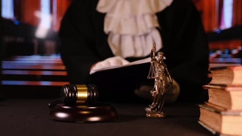 Closeup of Wooden Gavel Law Books and Statue of Lady Justice Placed on Courtroom Desk