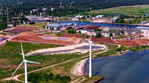 Wind turbines spinning over rural Latvia landscape with village in the background scene