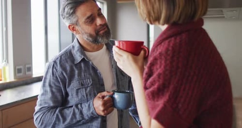 Couple Conversing, Holding Mugs, in Bright Home