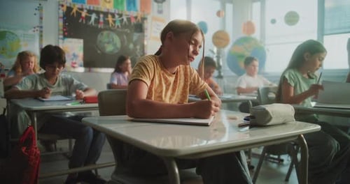 Elementary School Students Sitting at Desks Writing Exam or Lecture in Modern Classroom