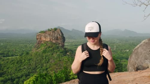 Active Woman Treks Hill Against Sigiriya Rock Backdrop Hiker with Backpack Reaches Summit Enjoys
