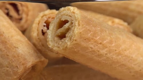 Crispy waffle tube without filling rotates in glass bowl. Delicious waffle roll dessert. Homemade