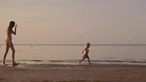 A Beautiful and Peaceful Sunset at the Beach Where a Loving Mother and Her Child Joyfully Play