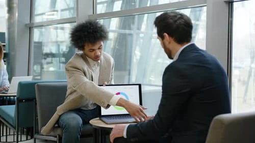 Businessmen Discussing Strategy on Laptop in Modern Office
