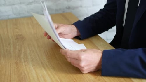Businessman looking through a pile of job applications. The man flicks through the papers