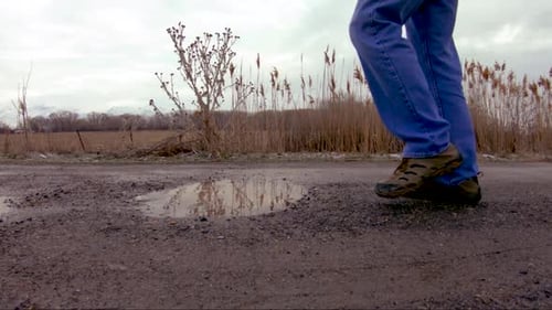 Close up of a puddle that a man steps in while walking by - slow motion