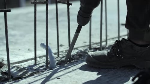 Construction Worker Drilling Concrete Foundation with Power Tool