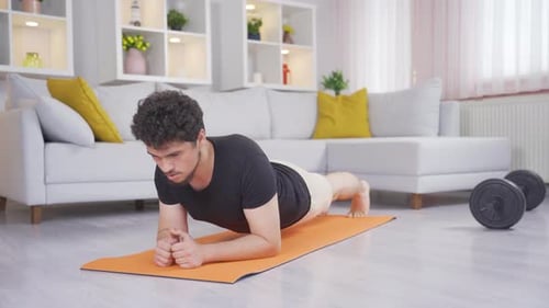 Young Adult Doing Plank Exercise on Mat Indoors