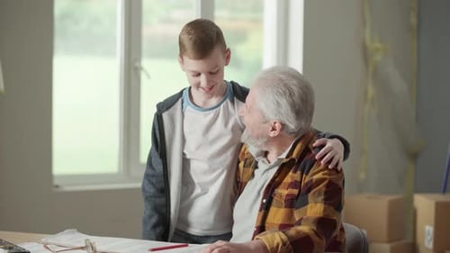 Grandson Friendly is Hugging His Grandfather Who is Showing and Explaining the Notes on the Repair