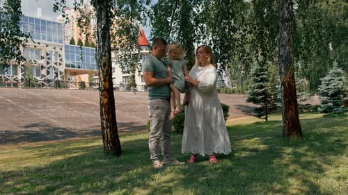 Portrait of a smiling young family mom dad and little daughter family on a walk in the park happy