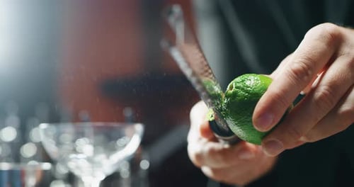 Close up of a professional bartender is preparing an alcoholic cocktail with lime