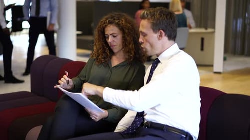 Happy business colleagues discussing project paperwork together in modern office