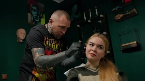Piercing studio interior - piercing master makes a piercing to a girl, ear piercing