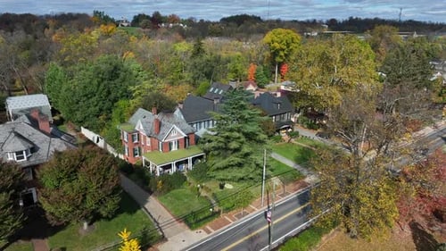 Aerial view of a suburban street with traditional houses amidst colorful autumn foliage.
