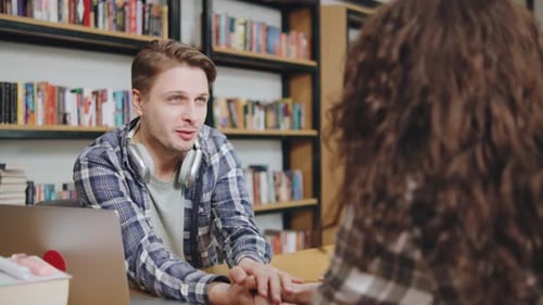 De jeunes adultes participent à une discussion intense dans une bibliothèque confortable remplie de livres pendant la