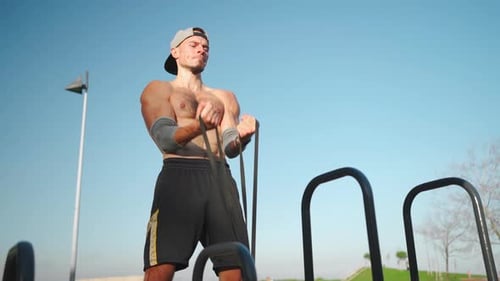Shirtless Man Exercising with Resistance Band Outdoors