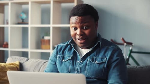 Man Reacting to Laptop Screen while Relaxing at Home