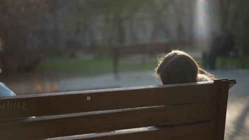Two Teens Sitting on Bench in City Park