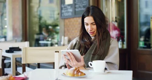 One morning a beautiful elegant woman eats breakfast at the outdoor cafe with a coffee and croissa