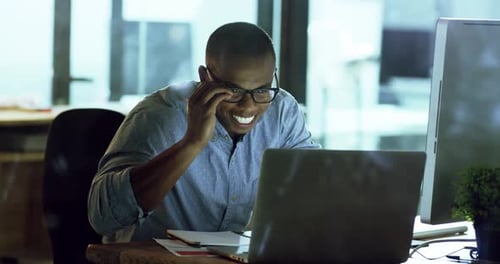 Young Man Working on Laptop in Office at Night