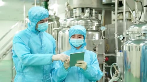 Medical staff in protective clothing using tablets to walk and communicate in factory